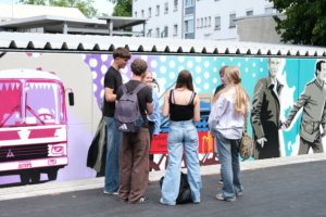 Schülerinnen und Schüler vor dem Graffiti von 3steps am Lern- und Gedenkort