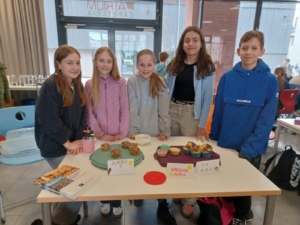 Sophie Freundorfer, Johanna Brand, Svea Schwarz, Suri Metzger, Mykhailo Verkalets, Evgenia Alexopoulos und Abdul-Mannan Aslam in der Cafeteria beim Verkauf der Muffins